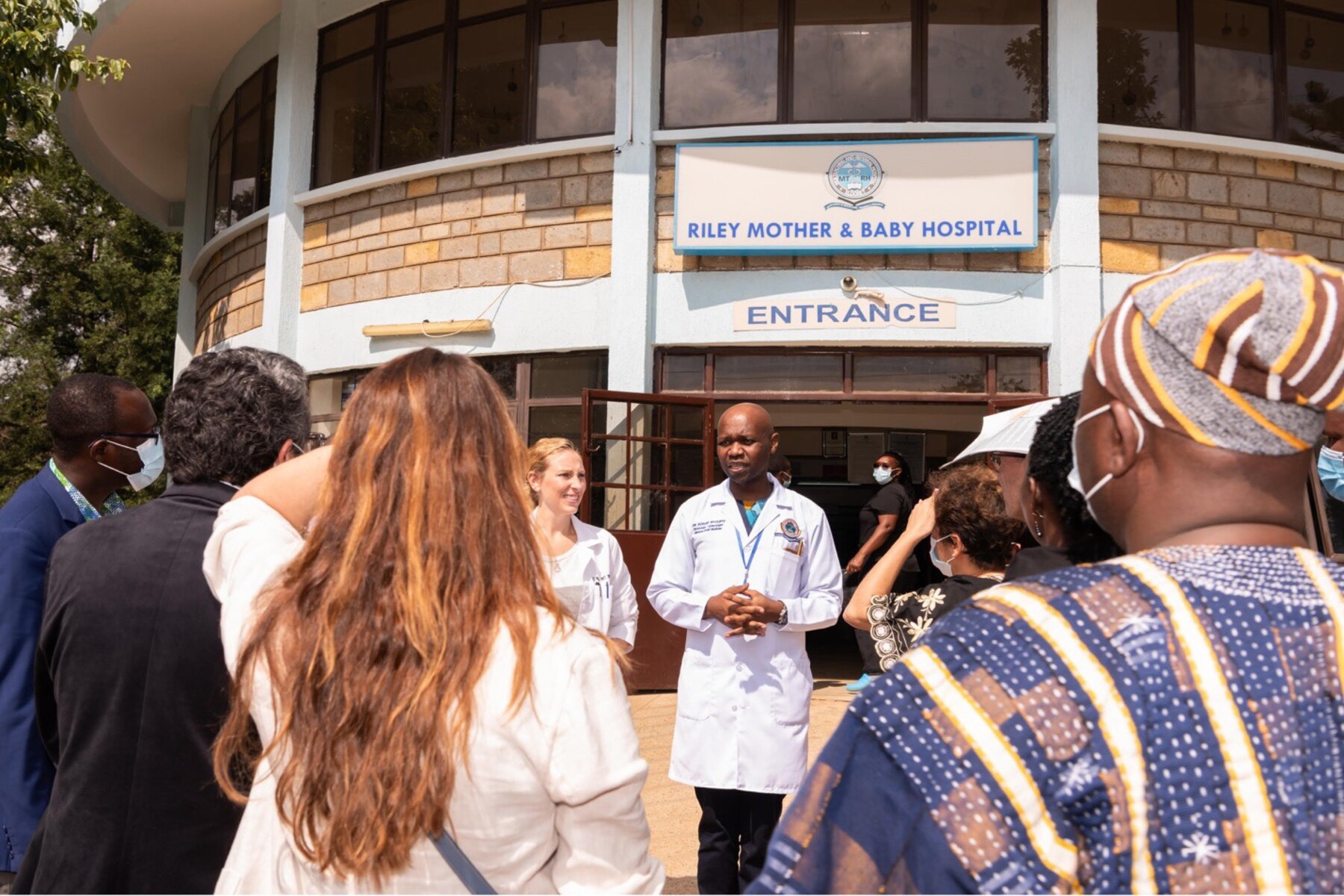 Doctor in lab coat speaks to crowd outside hospital